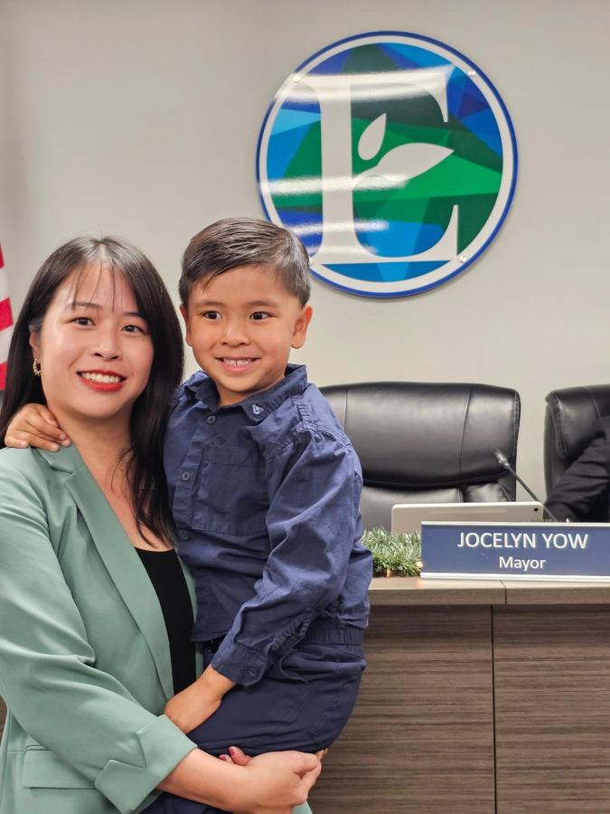 As a working mother and the only woman on her city council, Eastvale Mayor Jocelyn Yow has championed family-friendly improvements. Photo courtesy of Jocelyn Yow. Jocelyn Yow holding her son in front of her mayor's seat