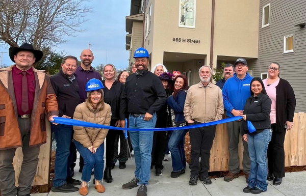 Group of people with long ribbon in front of new housing development
