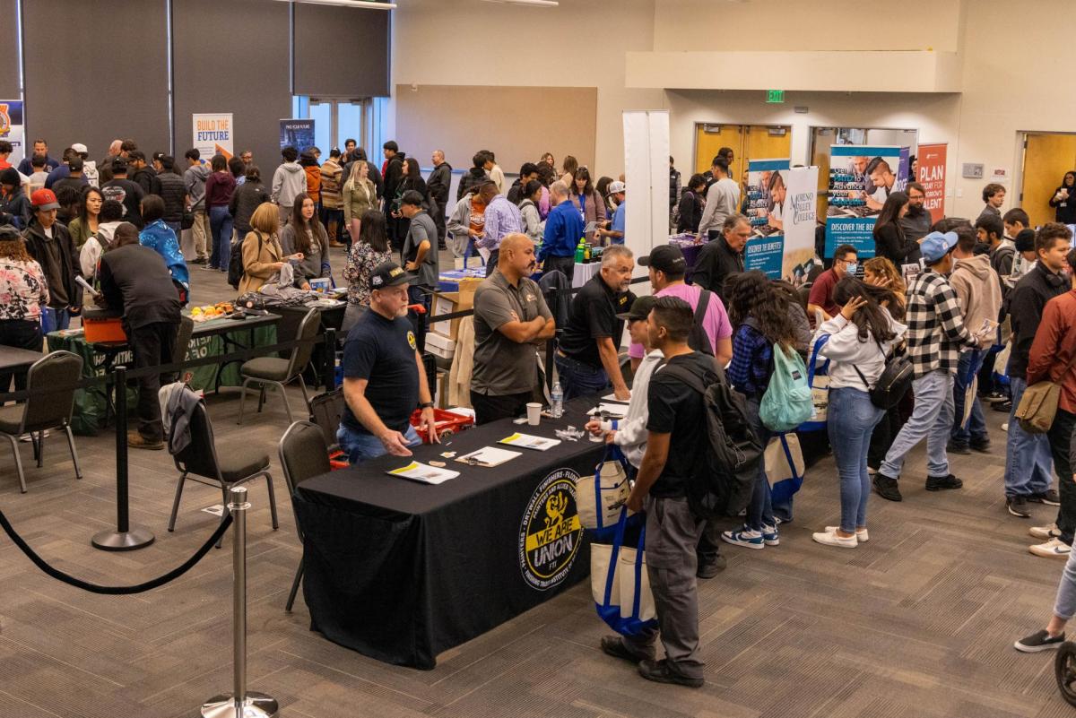 A group of high schoolers meeting with potential employeers at a career fair. 