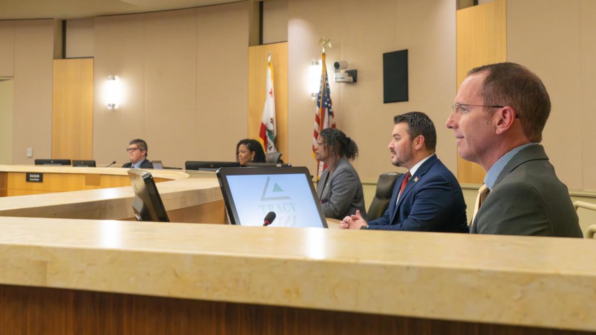 A group of city council members looking forward at their residents during a council meeting. 
