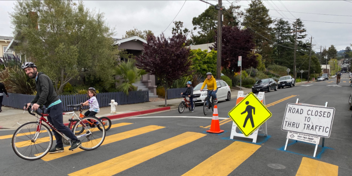 A family bikes on a residential road. A sign says the road is closed to thru traffic.