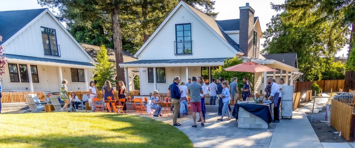 People socializing outside neighborhood cottages