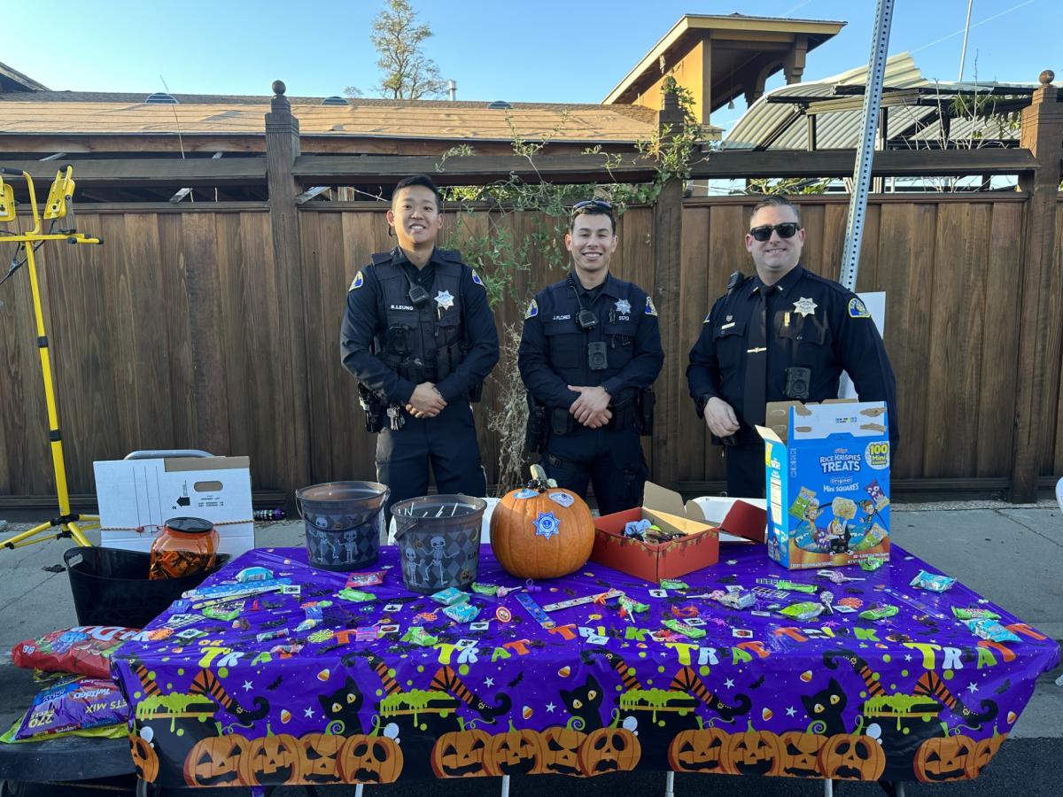 Three police officers stand behind table at a block party event.