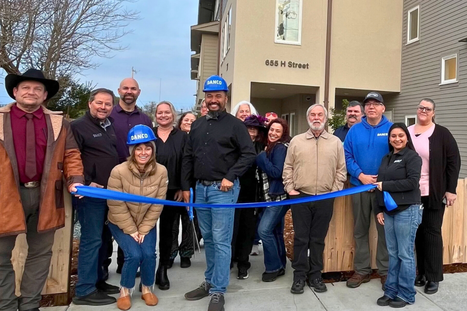 Group of people with long ribbon in front of new housing development