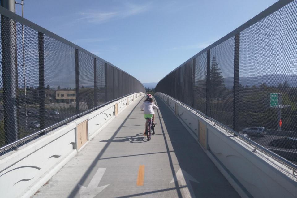 A child biking alone on a protected bike bridge. 
