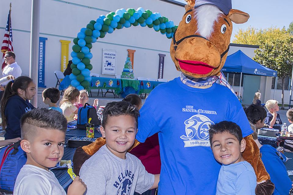 Santa Clarita mascot, Sammy Clarita, poses with children at a local event. 