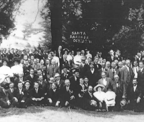 A group of mostly white men, and a few women, standing together for a photo in 1911.