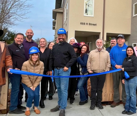 Group of people with long ribbon in front of new housing development