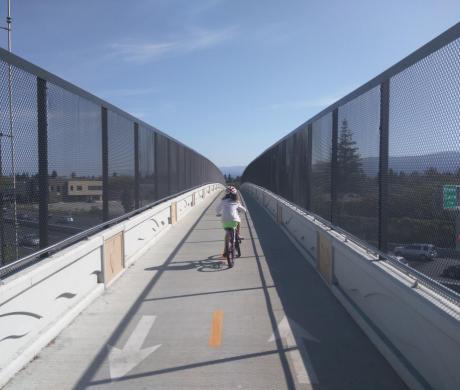 A child biking alone on a protected bike bridge. 