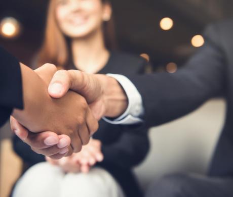 Two people shaking hands with an onlooker.