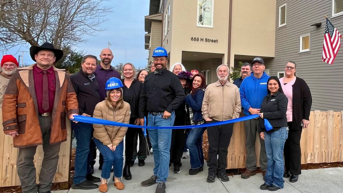 Group of people with long ribbon in front of new housing development